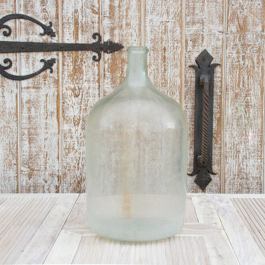 Large glass bottle on a wooden surface with a rustic wooden wall background