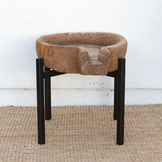 Round stone bowl on a black stand against a white wall.