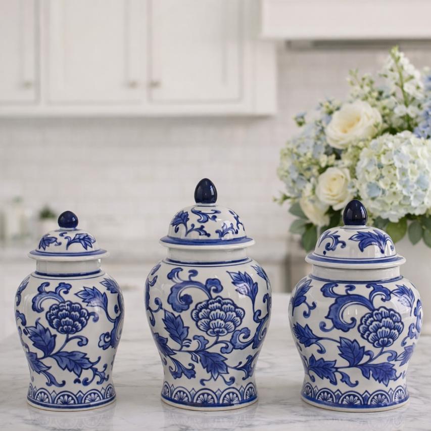 Three blue and white ceramic jars on a kitchen counter with flowers in the background.