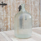 Large glass bottle on a wooden surface with a rustic wooden wall background
