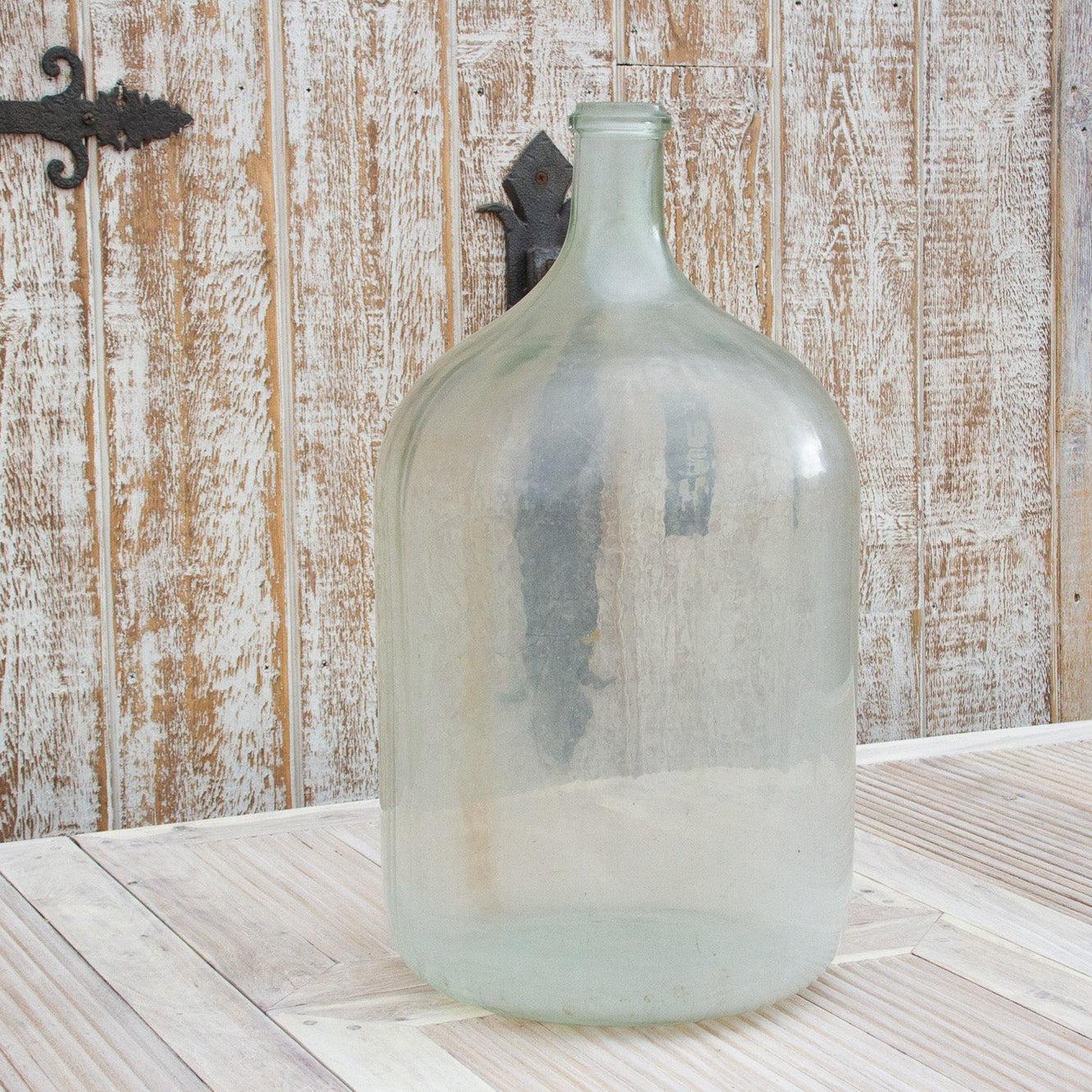 Large glass bottle on a wooden surface with a rustic wooden wall background