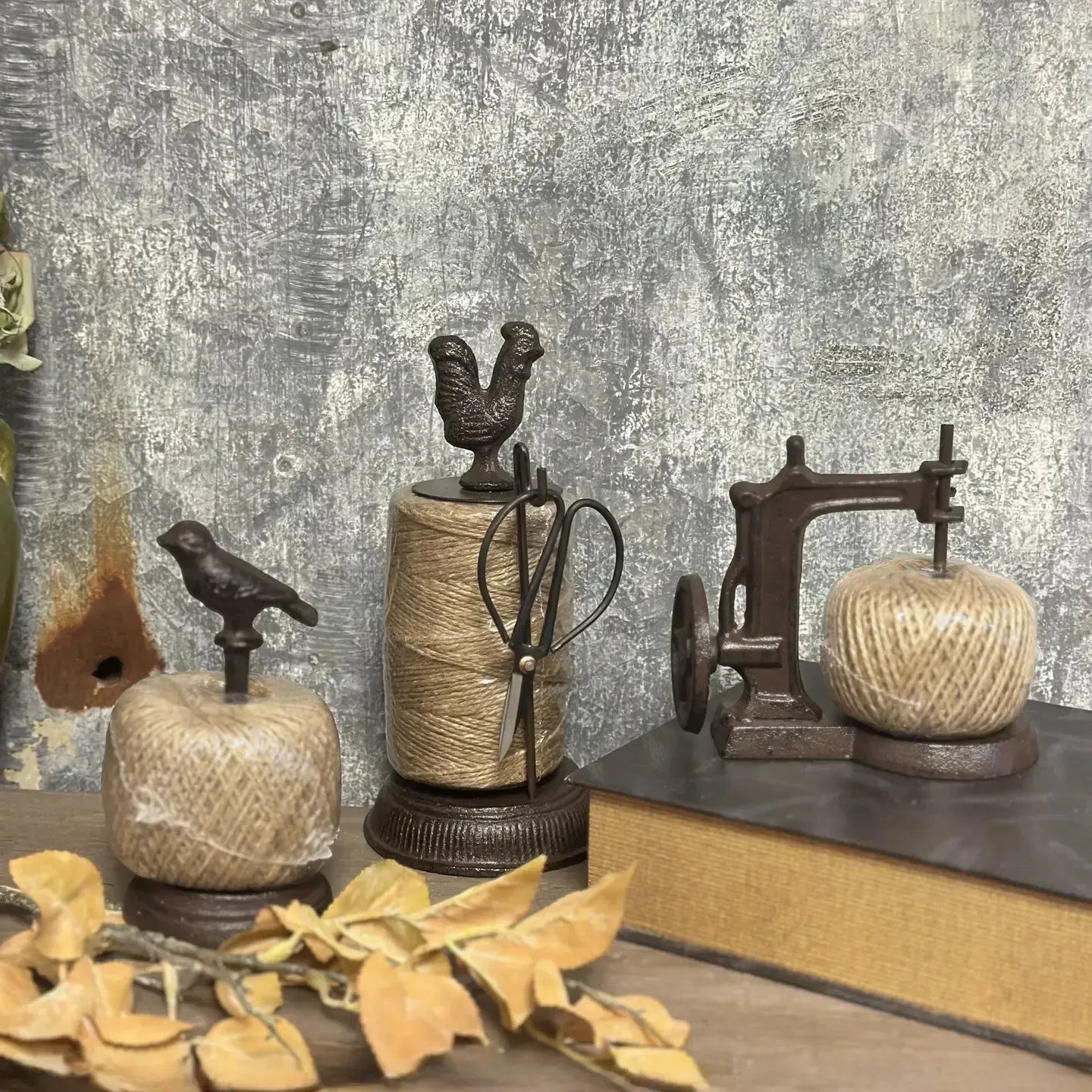 Decorative items including spools of twine, birds, and a sewing machine on a textured surface.