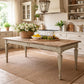Wooden dining table in a kitchen with flowers and fruit on top