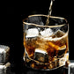 Glass of whiskey with ice being poured against a black background