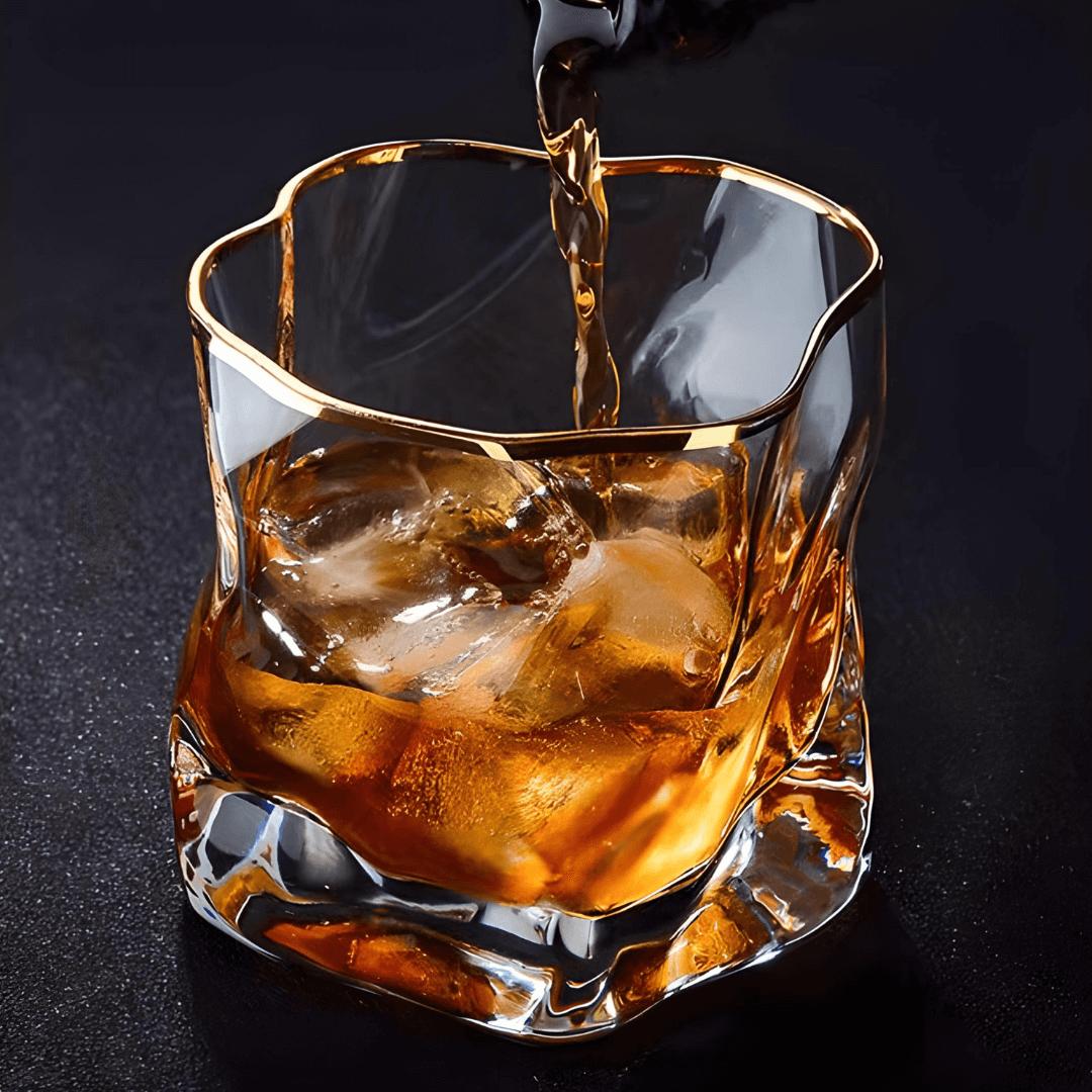Glass of whiskey with ice being poured on a dark background