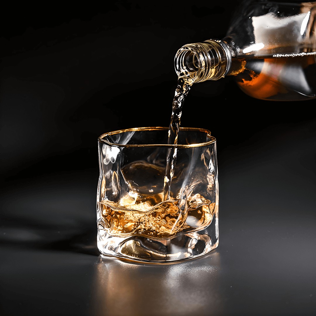 Whiskey being poured into a glass with ice cubes on a dark background