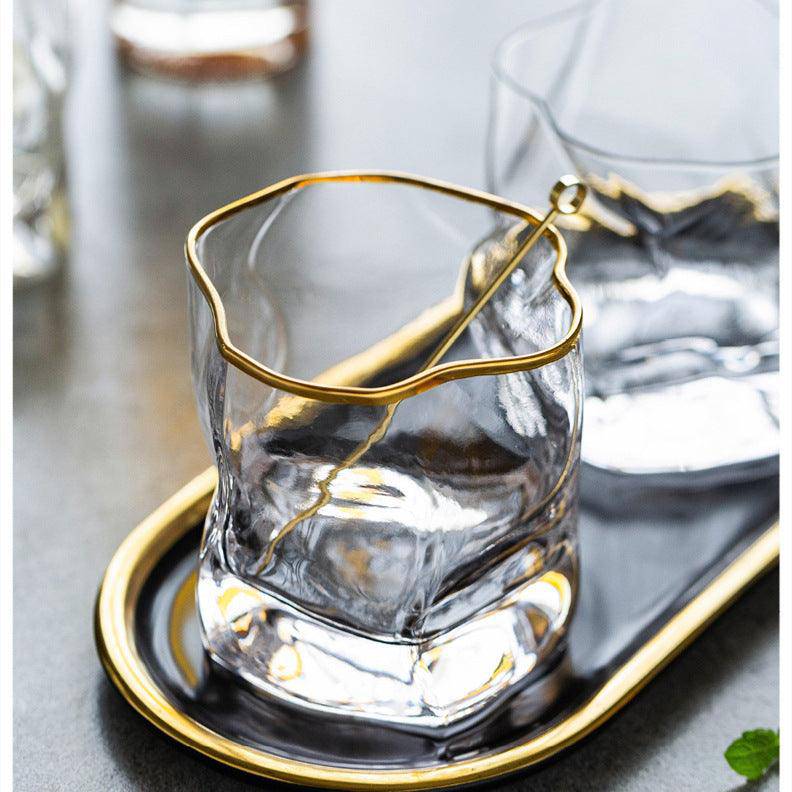 Clear glass tumbler with gold rim on a matching tray