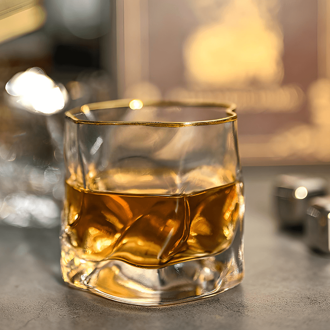 Glass of whiskey with a gold rim on a dark surface