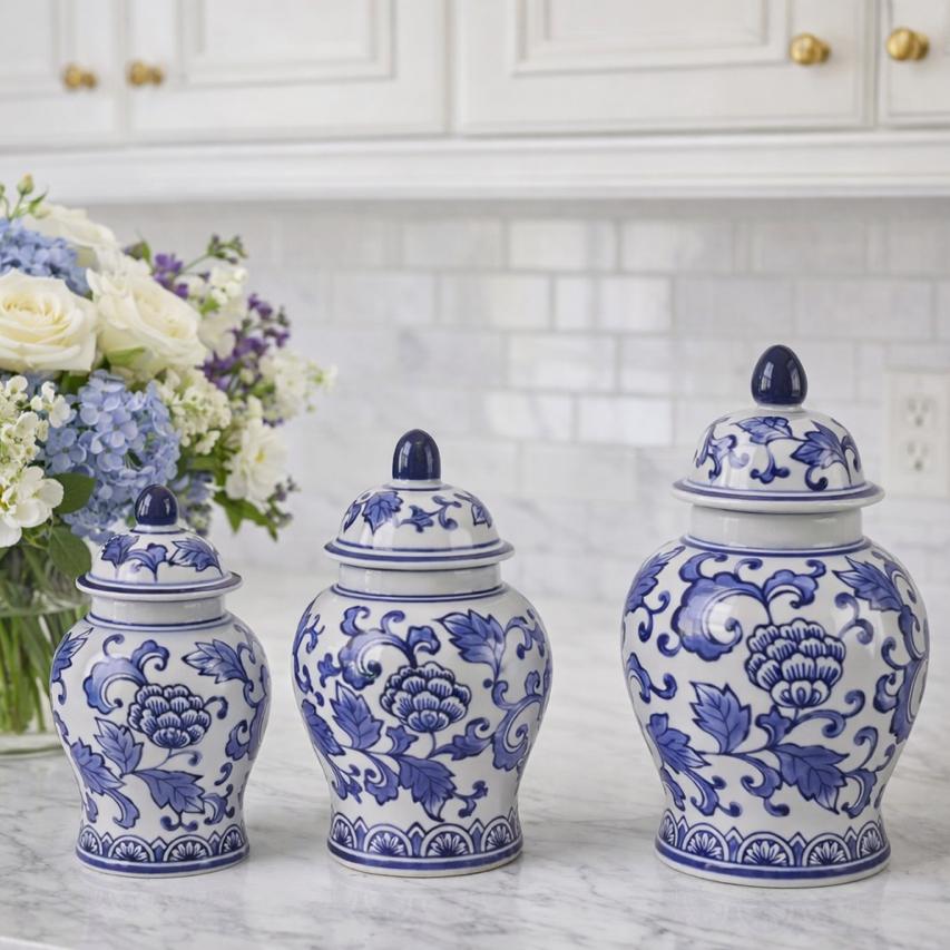 Set of three blue and white decorative jars on a kitchen counter with a bouquet of flowers.