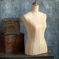Mannequin torso on a wooden surface with a textured blue wall background